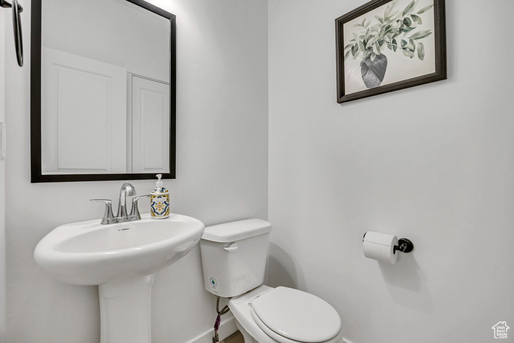 Half bath with toilet, baseboards, and a sink