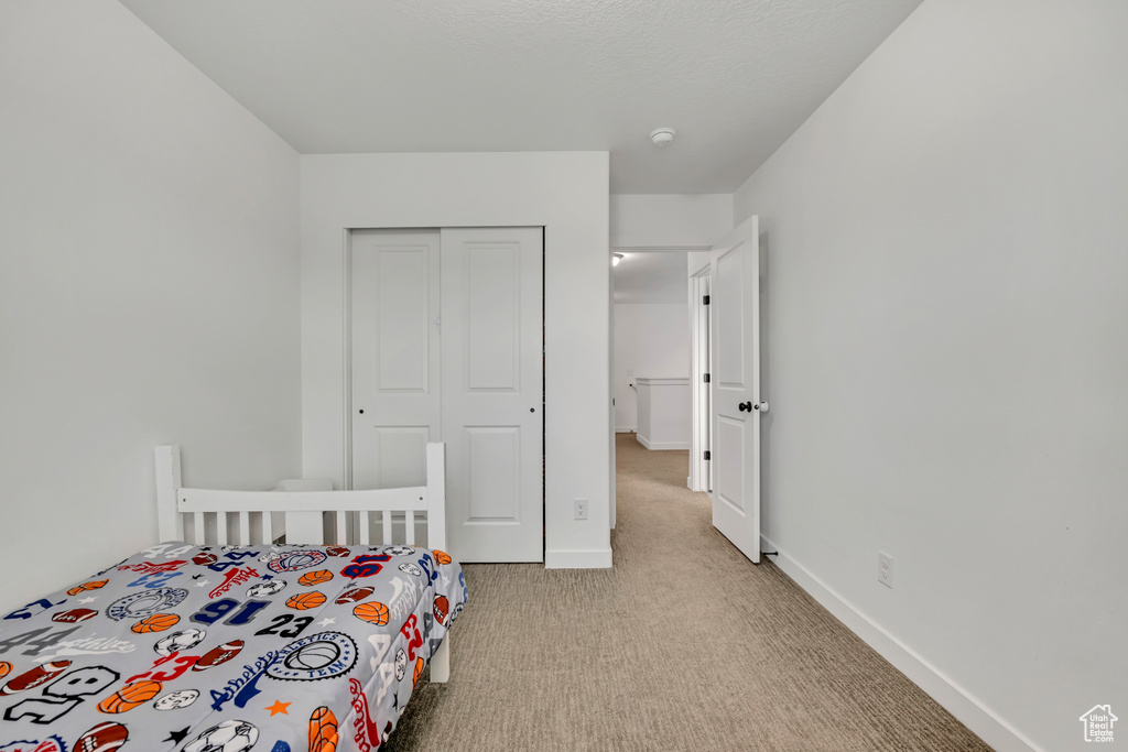 Bedroom featuring carpet flooring, a closet, and baseboards