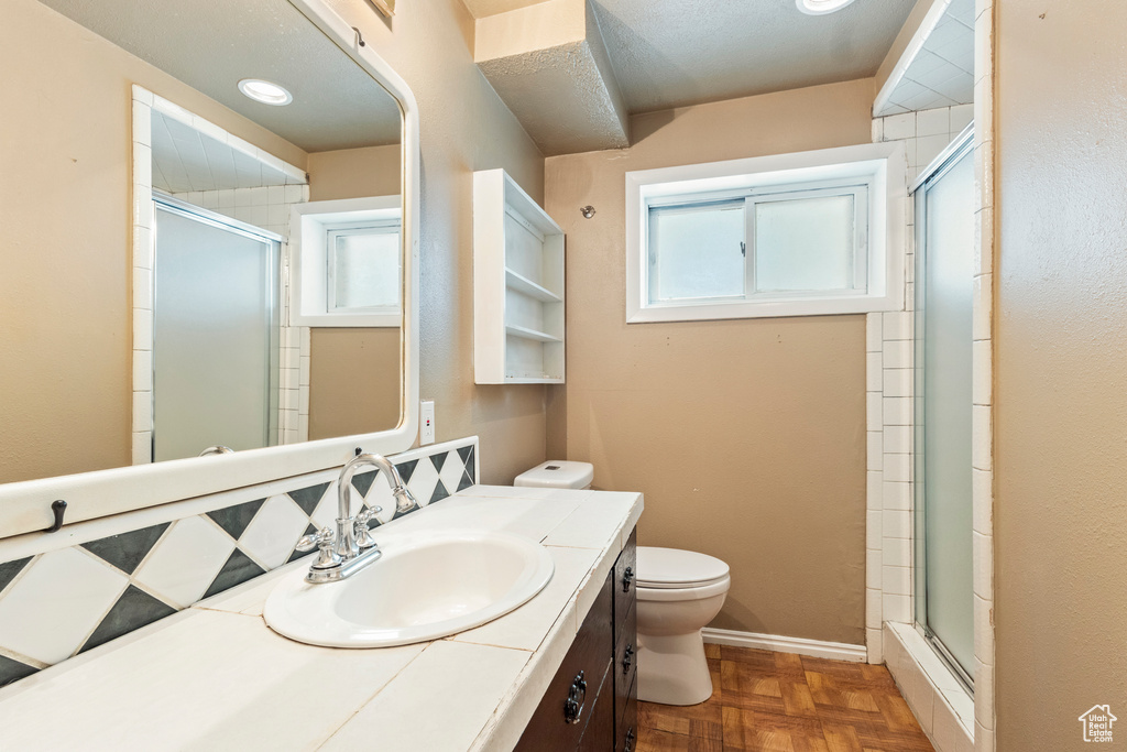 Bathroom featuring toilet, vanity, and a stall shower