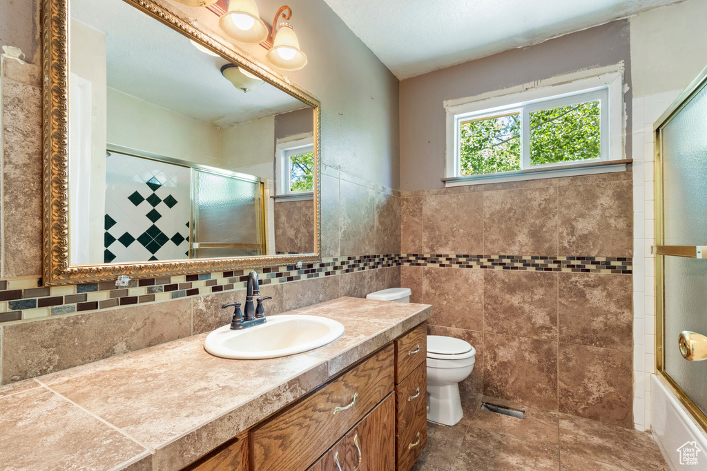 Bathroom with vanity, toilet, and tile walls