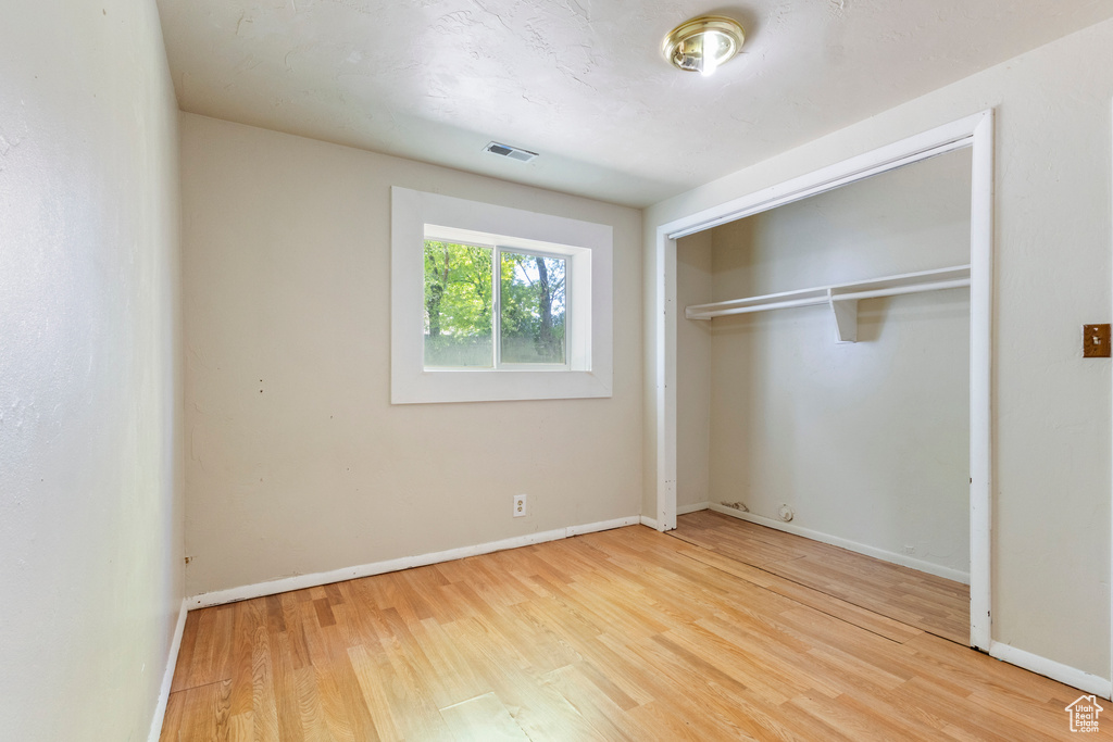 Unfurnished bedroom featuring wood finished floors, a closet, and baseboards