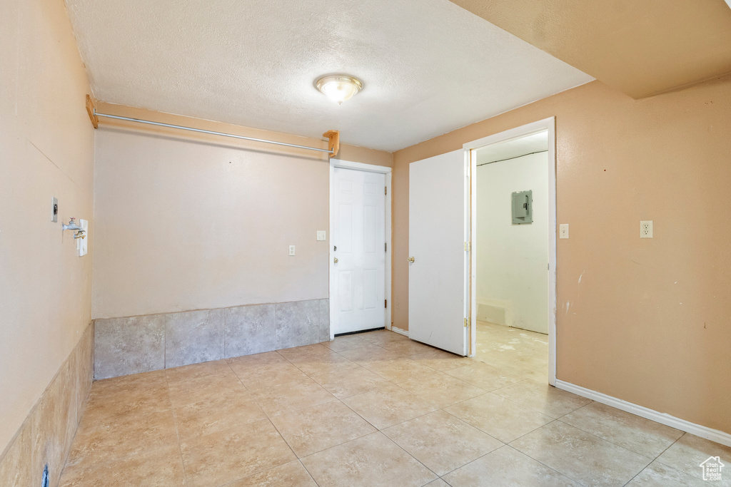 Unfurnished room featuring electric panel, tile patterned flooring, and a textured ceiling