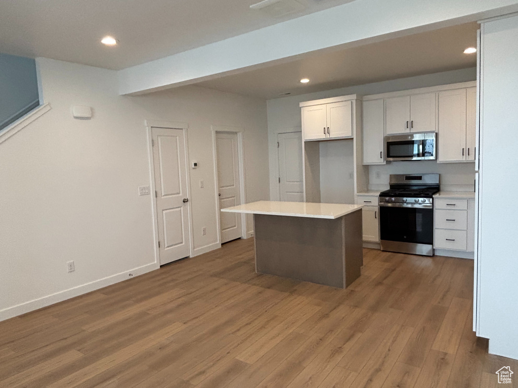 Kitchen featuring stainless steel appliances, white cabinets, light wood finished floors, recessed lighting, and light countertops
