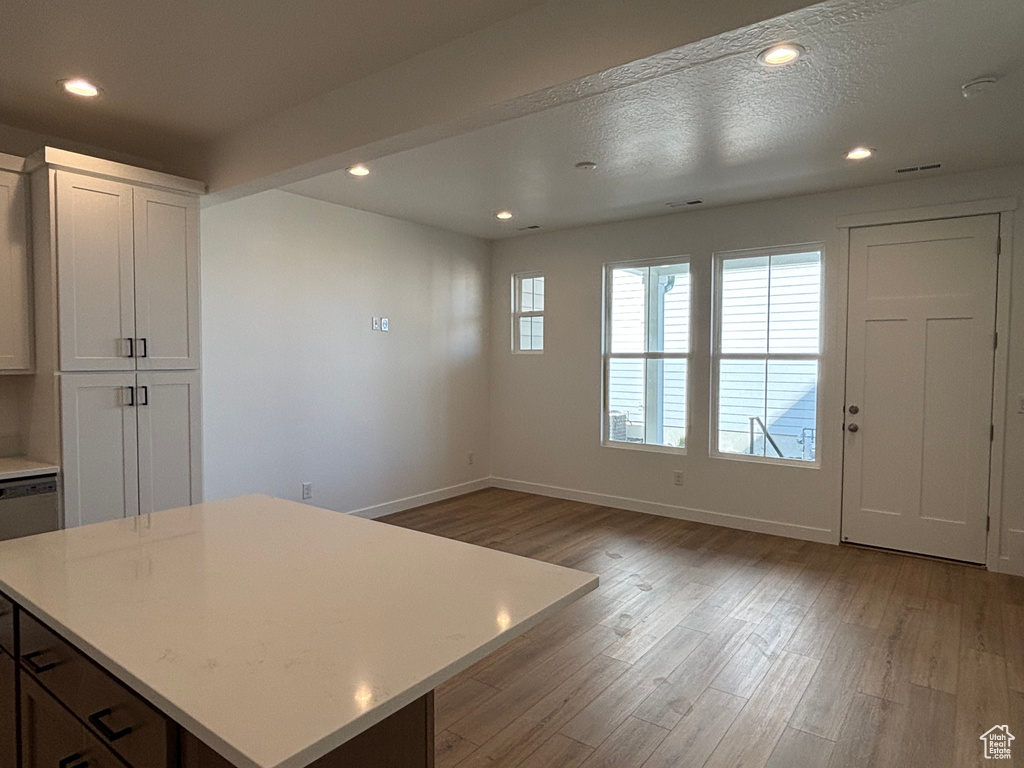 Kitchen with light wood-style floors, baseboards, light countertops, recessed lighting, and a center island