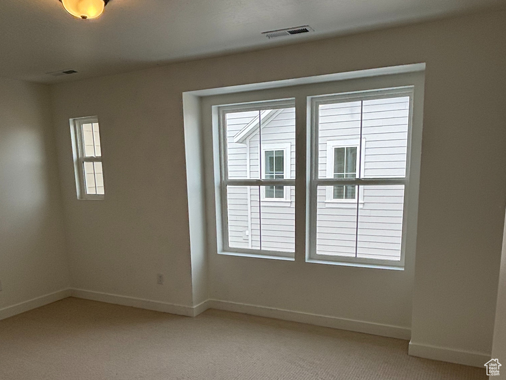 Empty room featuring light colored carpet and baseboards