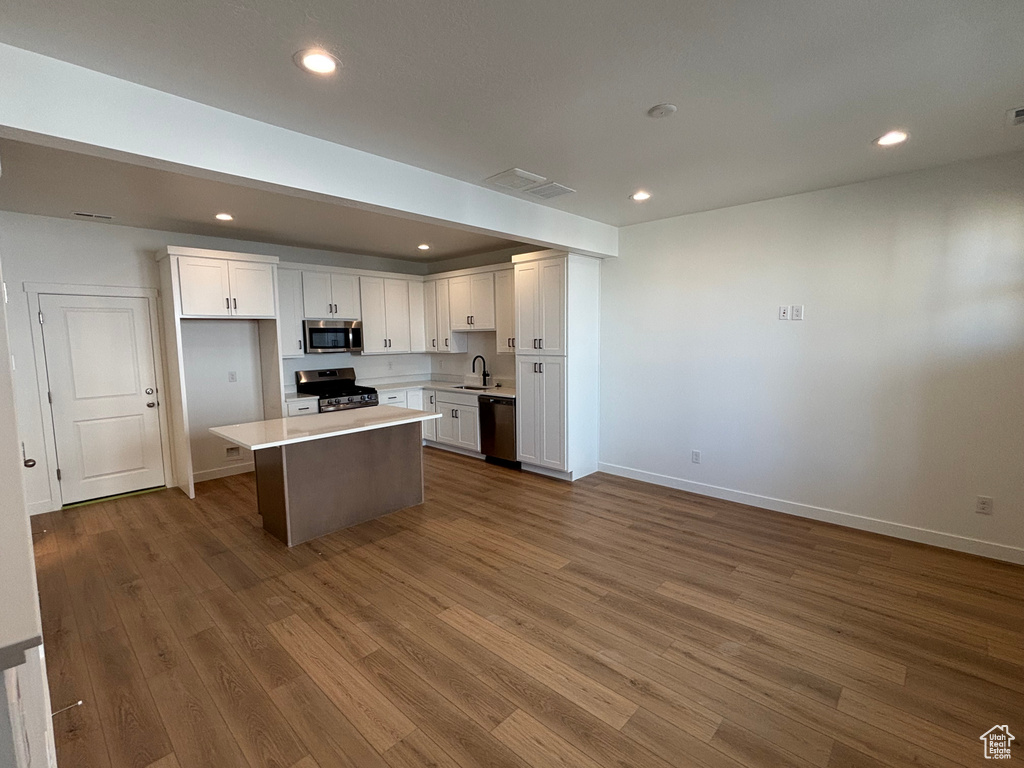 Kitchen featuring stainless steel appliances, a sink, white cabinets, dark wood-style flooring, and recessed lighting