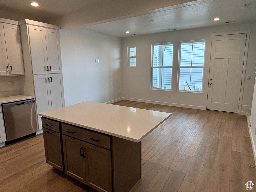 Kitchen with stainless steel dishwasher, light wood-type flooring, light countertops, baseboards, and recessed lighting