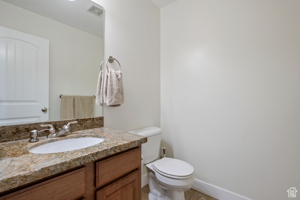 Bathroom with toilet, vanity, and tile patterned floors