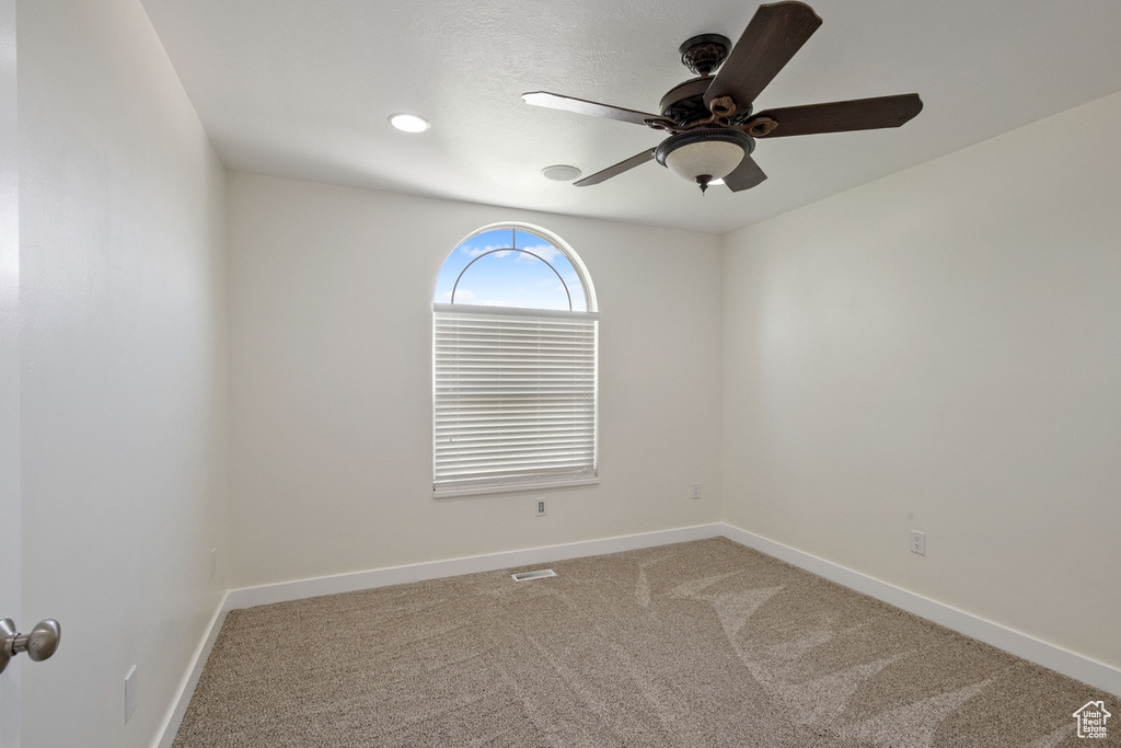 Carpeted spare room featuring ceiling fan and baseboards