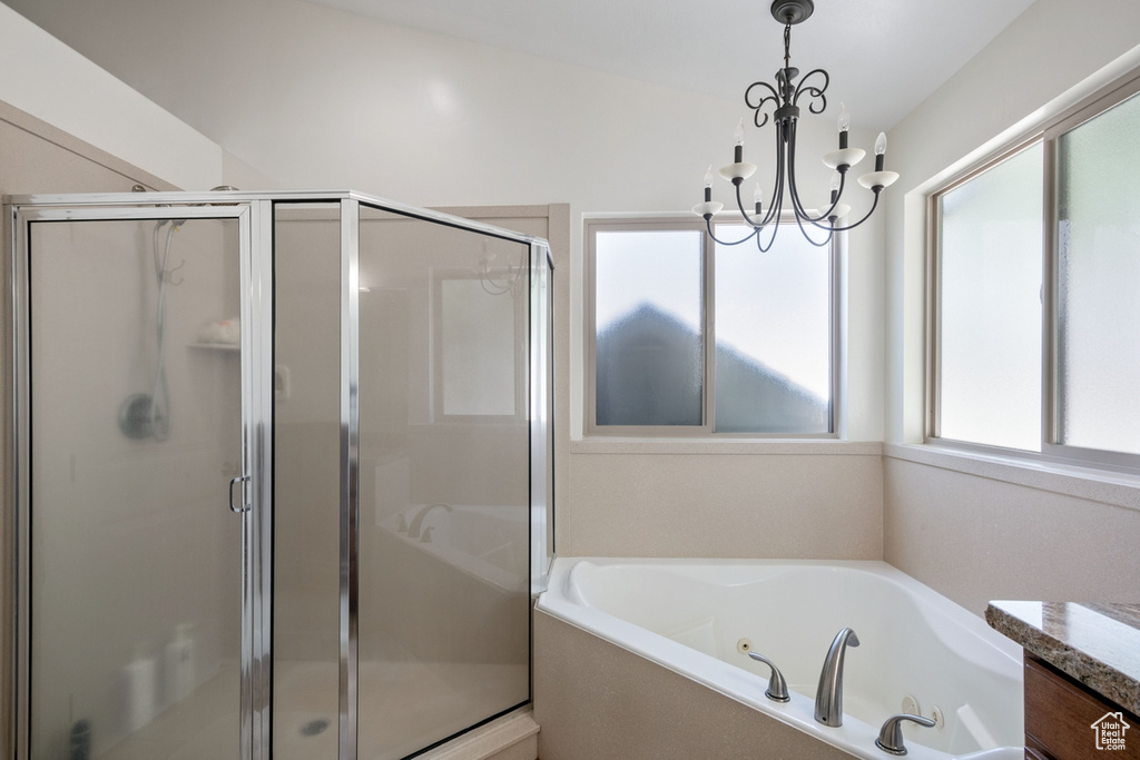 Bathroom with a stall shower, a chandelier, plenty of natural light, and a whirlpool tub