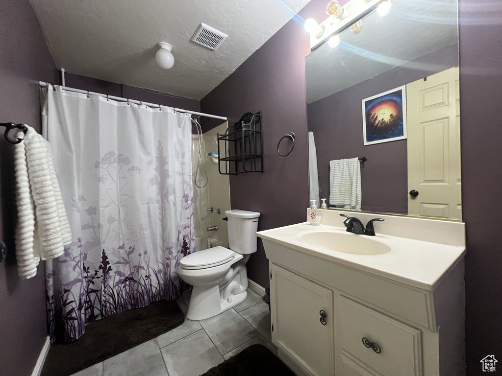 Bathroom featuring toilet, vanity, tile patterned flooring, baseboards, and a shower with curtain