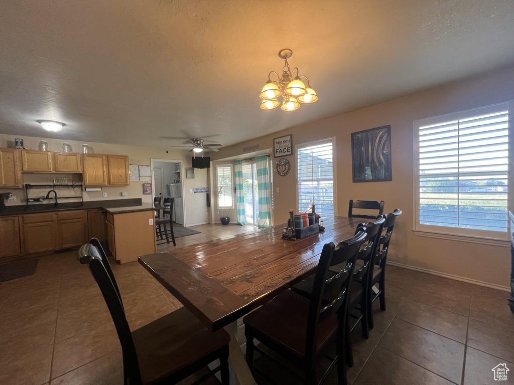 Tiled dining area featuring a chandelier, a ceiling fan, a sink, and baseboards