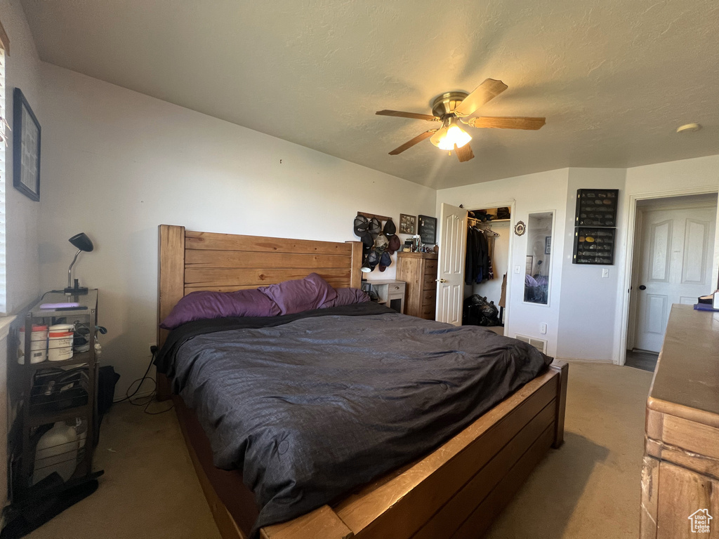 Carpeted bedroom with a ceiling fan, a closet, and a spacious closet