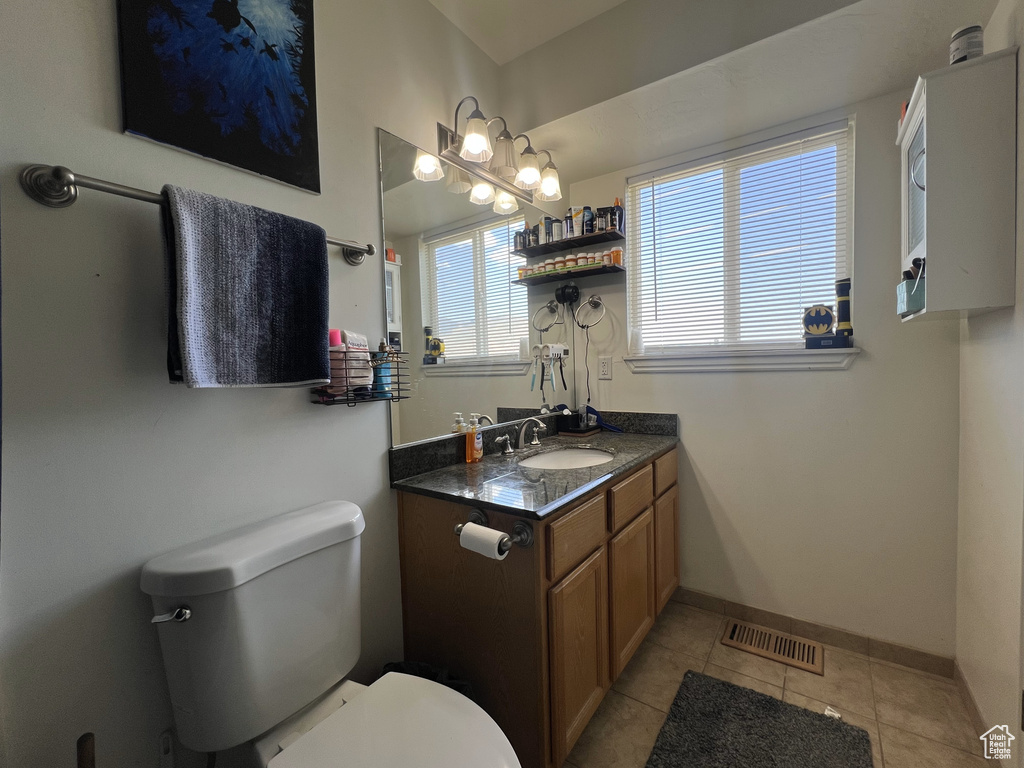 Bathroom featuring toilet, vanity, tile patterned floors, and baseboards