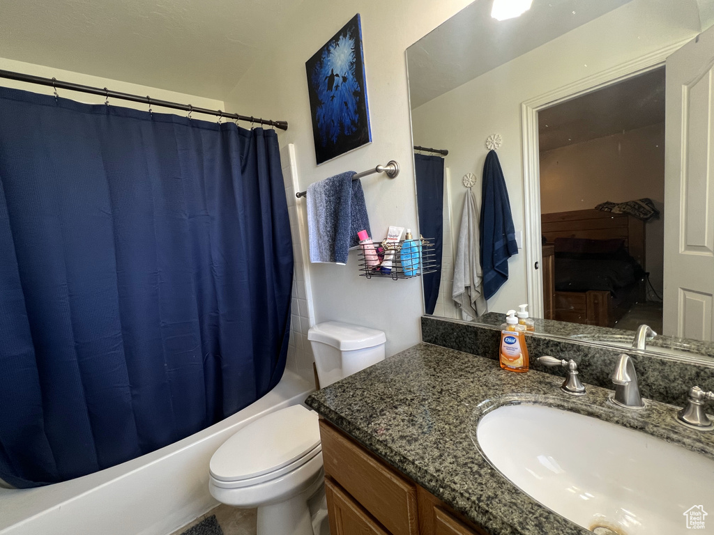 Ensuite bathroom featuring shower / bath combo, vanity, and toilet