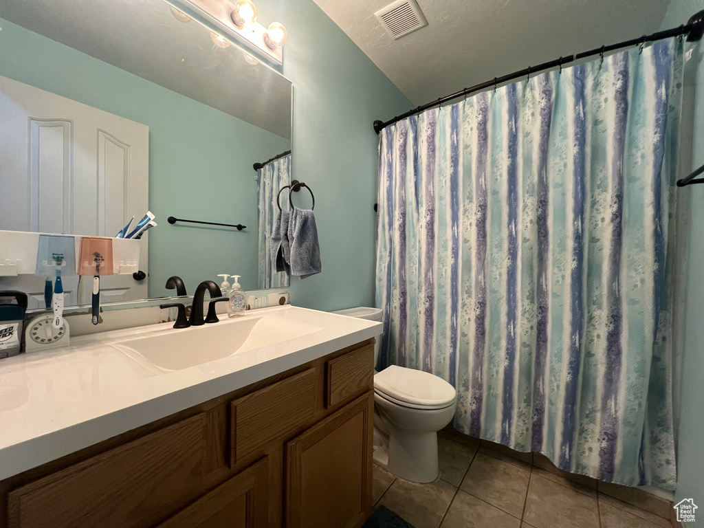 Full bathroom with toilet, tile patterned flooring, and vanity