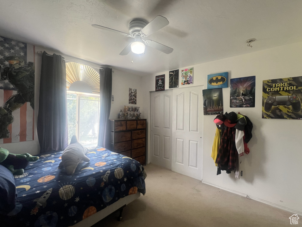 Carpeted bedroom featuring ceiling fan and a closet