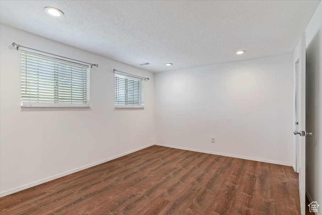 Empty room featuring wood finished floors, recessed lighting, baseboards, and a textured ceiling