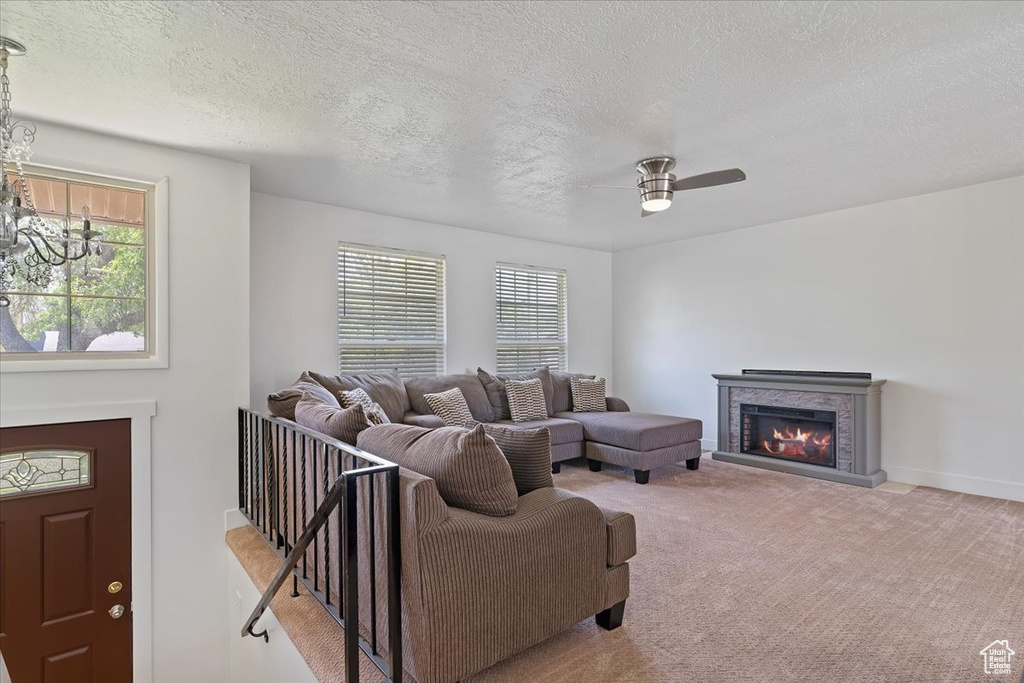 Carpeted living area with a glass covered fireplace, ceiling fan, a textured ceiling, and baseboards