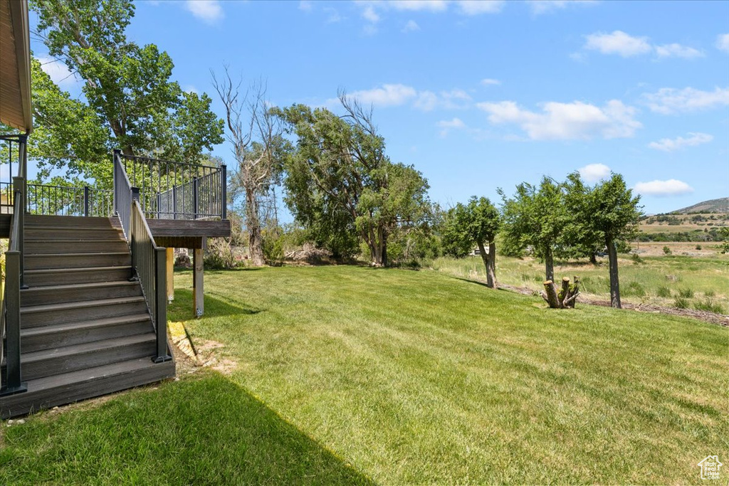 View of green lawn with stairway and a deck