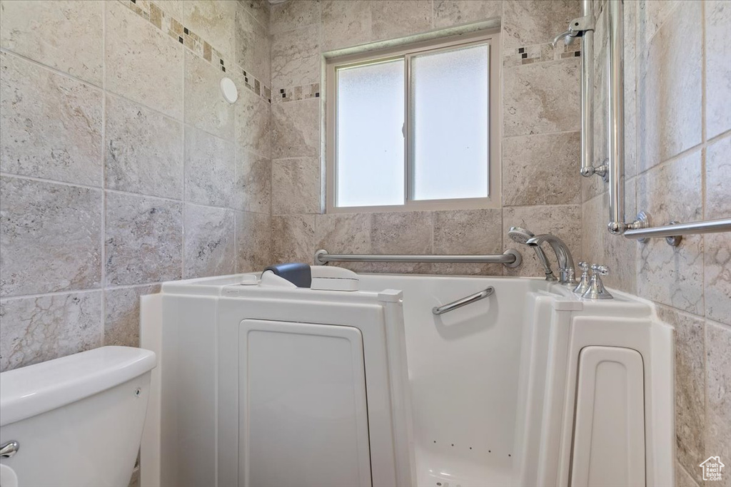 Full bath featuring tile walls, a garden tub, and toilet