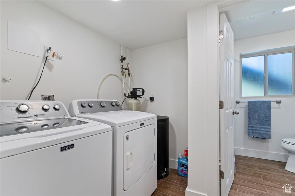 Laundry room featuring washing machine and clothes dryer, wood finished floors, and baseboards