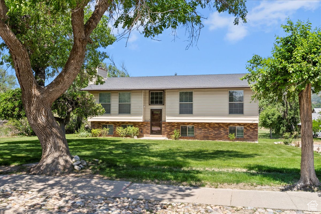 Bi-level home featuring a front yard, a chimney, and brick siding