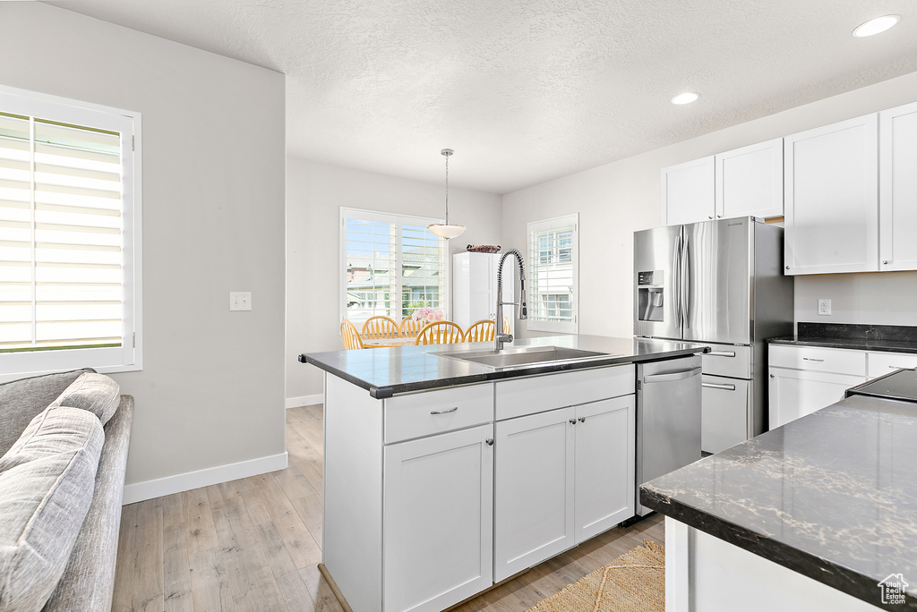 Kitchen featuring stainless steel appliances, a sink, light wood-style flooring, recessed lighting, and white cabinets
