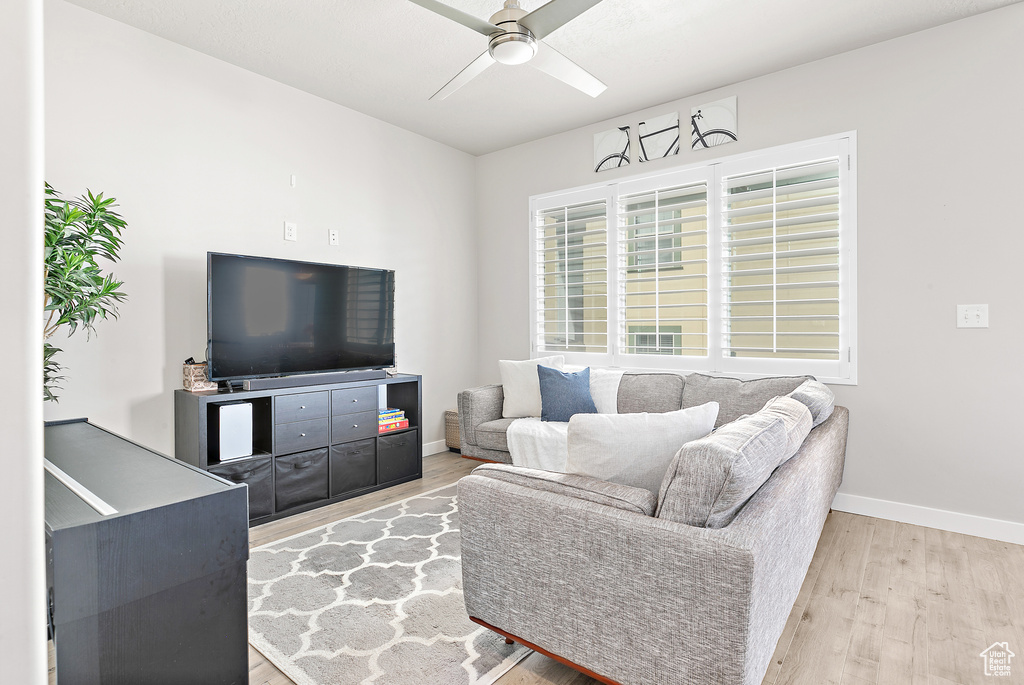 Living room with light wood-type flooring, ceiling fan, and baseboards