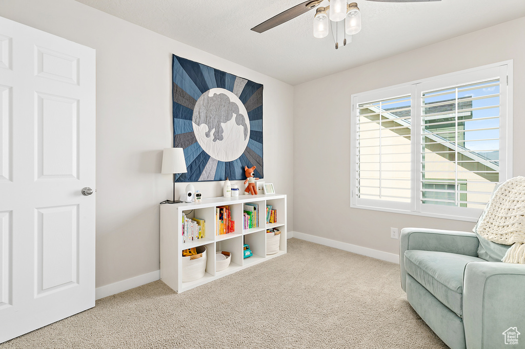 Sitting room with carpet floors, a ceiling fan, and baseboards