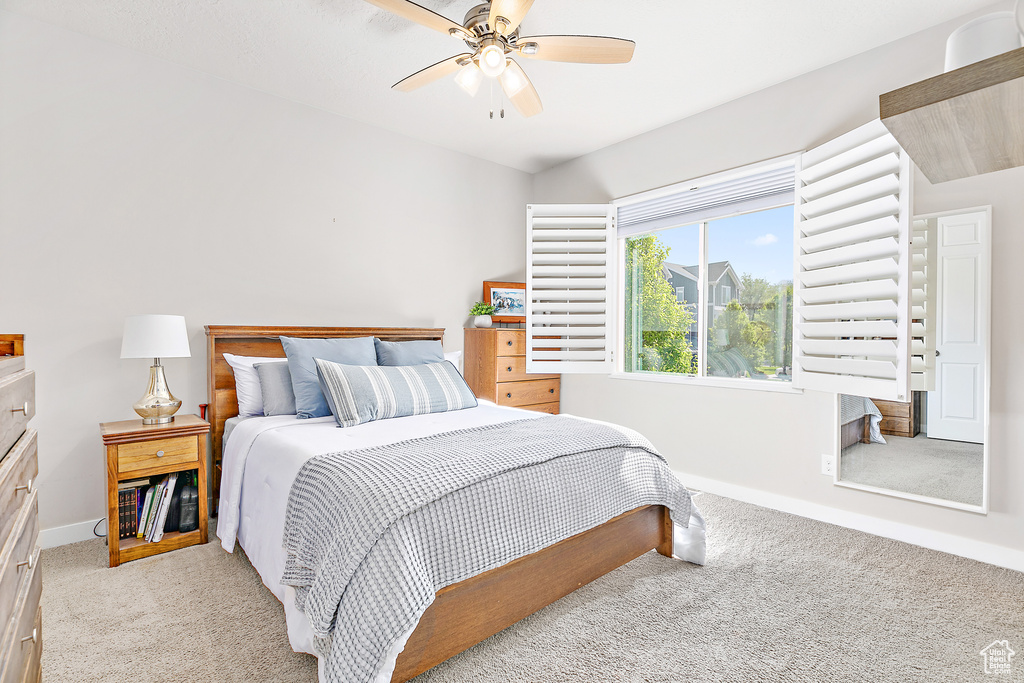Bedroom with light carpet, baseboards, and a ceiling fan