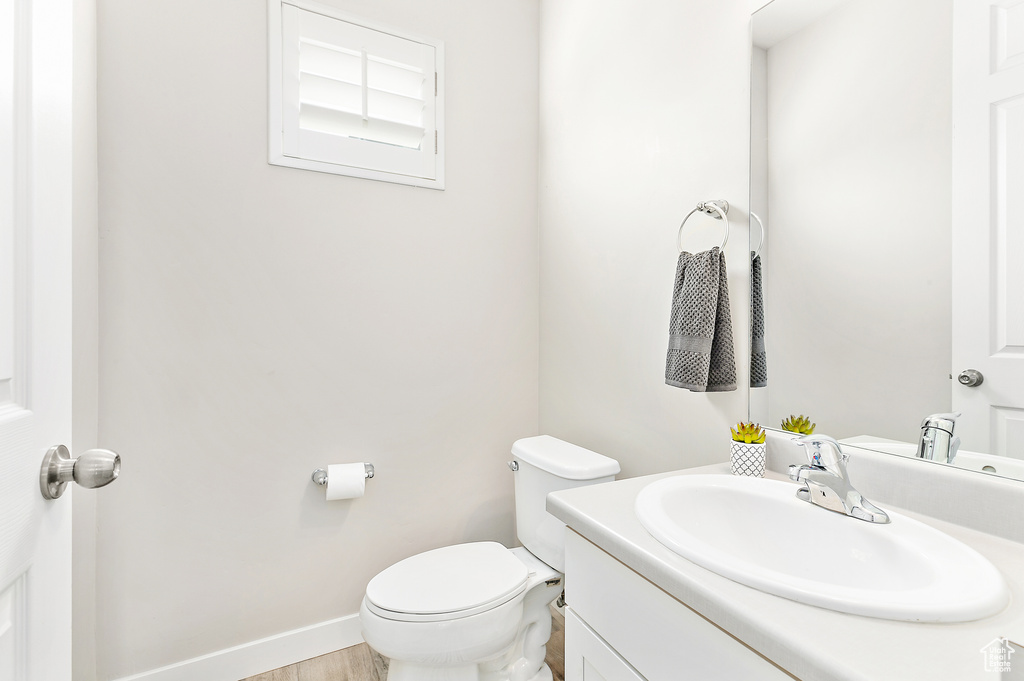 Bathroom featuring vanity, toilet, baseboards, and wood finished floors