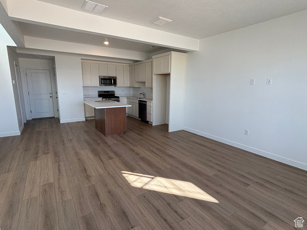 Kitchen with stainless steel microwave, stove, dishwashing machine, a sink, and dark wood finished floors