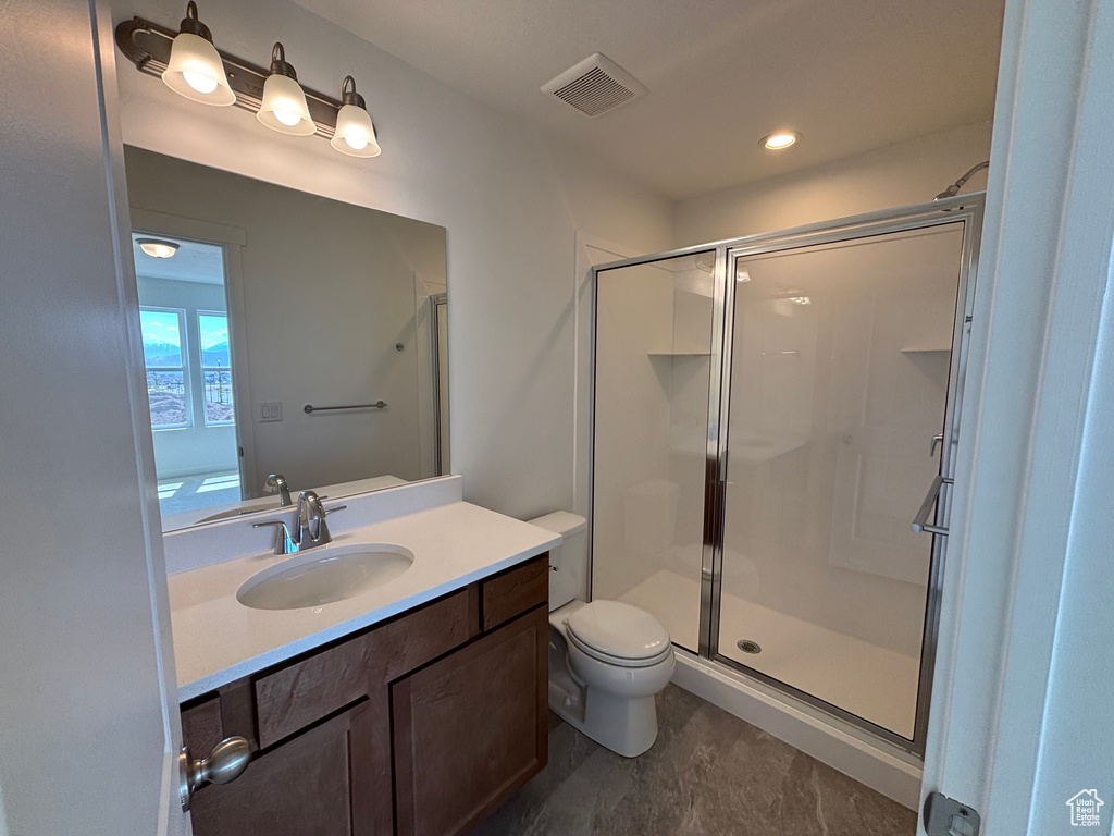 Bathroom featuring a shower stall, vanity, and toilet