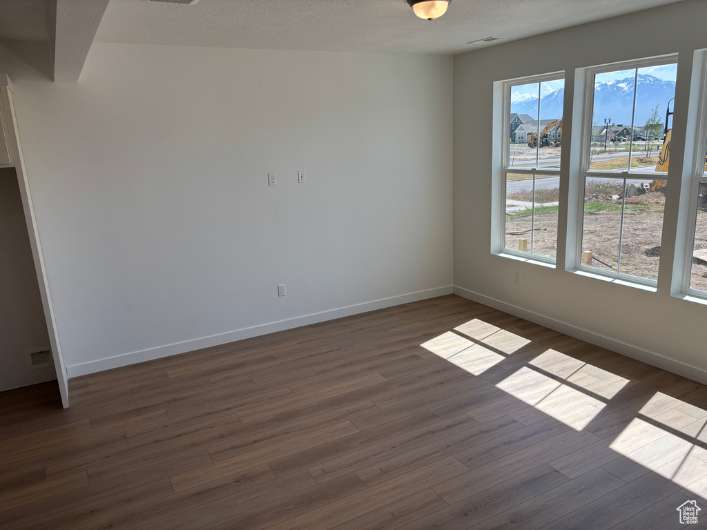 Empty room with dark wood-style floors, baseboards, and healthy amount of natural light
