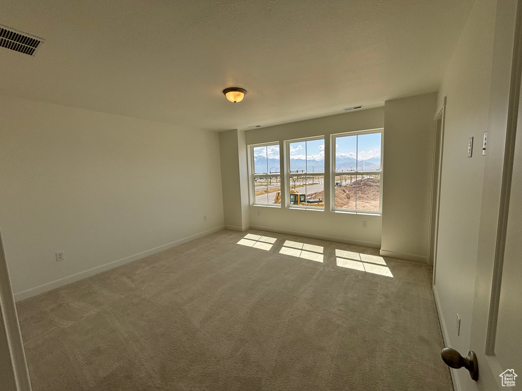 Empty room with light colored carpet and baseboards