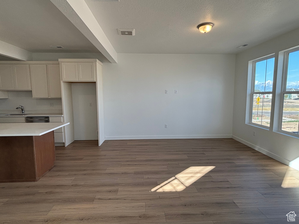 Kitchen with a sink, light countertops, wood finished floors, baseboards, and white cabinets