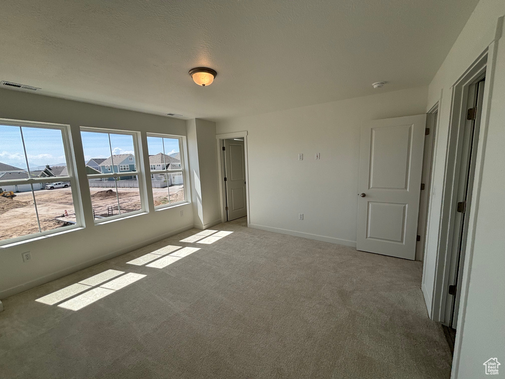 Unfurnished bedroom featuring light colored carpet and baseboards