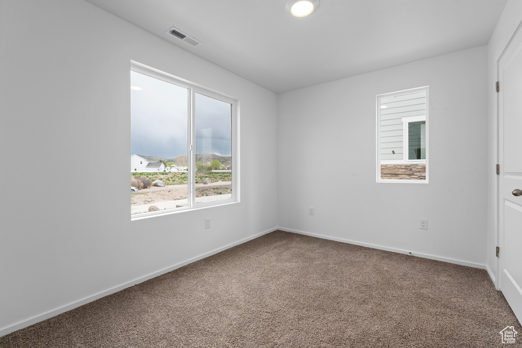 Carpeted spare room featuring baseboards