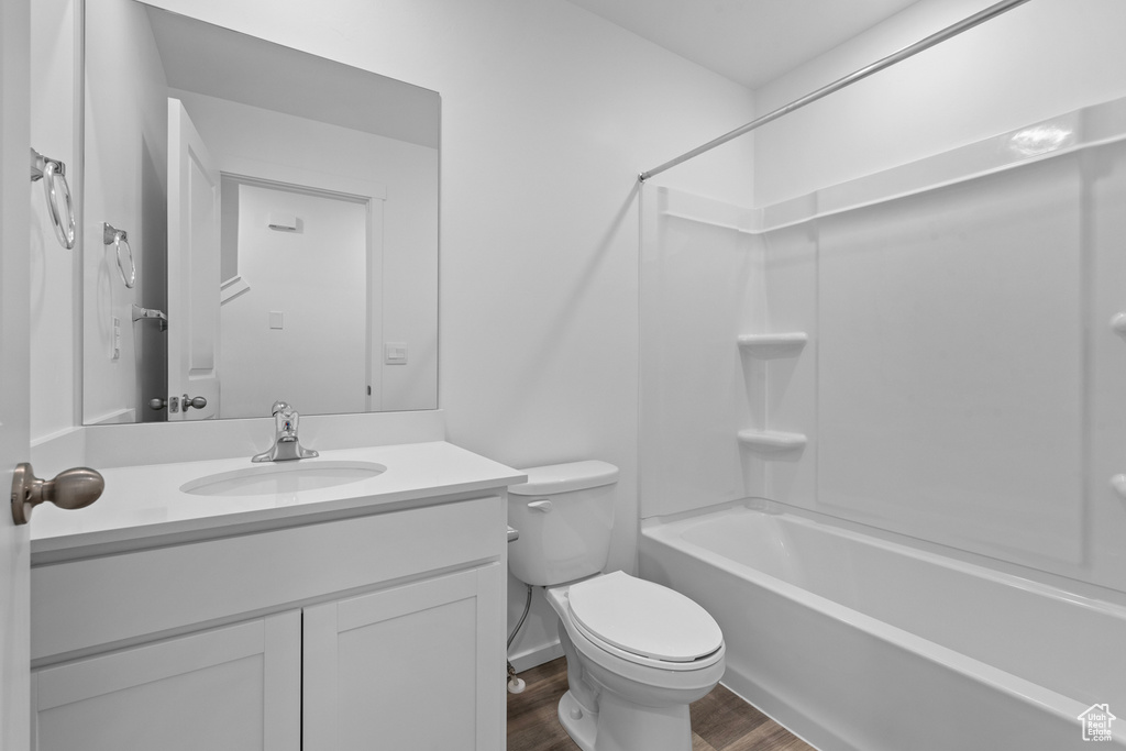 Bathroom featuring wood finished floors, vanity, toilet, and shower / bathtub combination