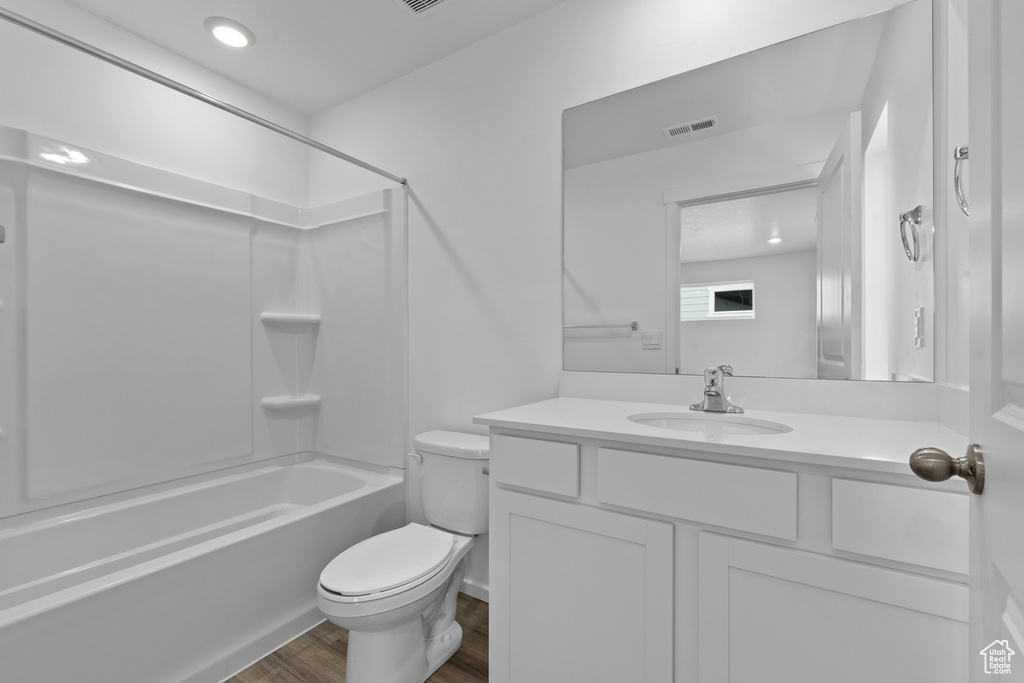 Bathroom featuring toilet, wood finished floors, vanity, shower / bathtub combination, and recessed lighting