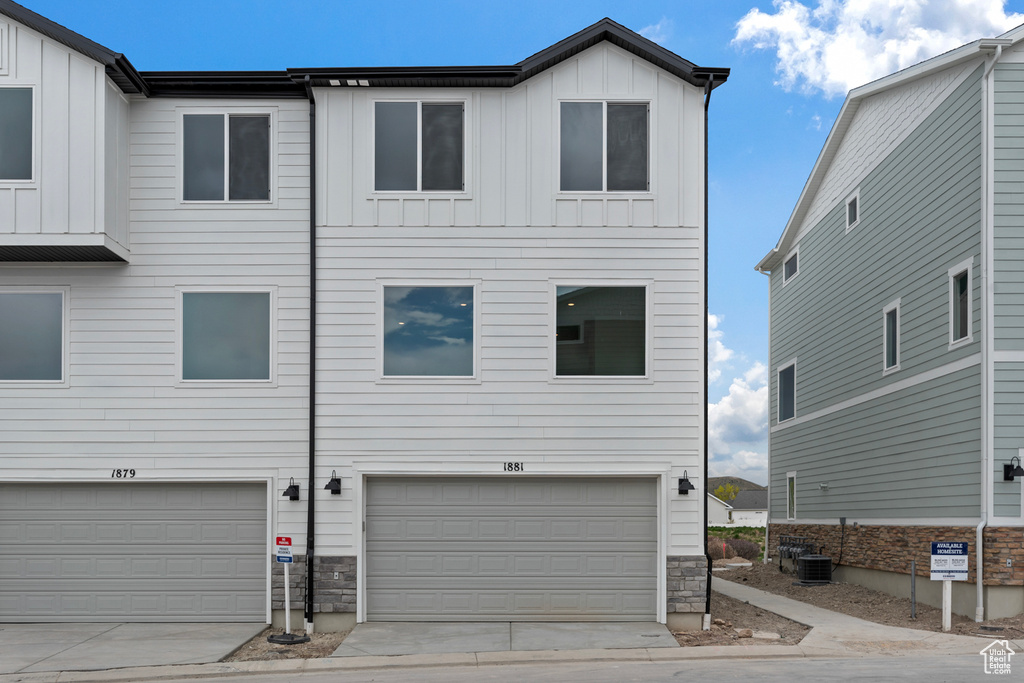 View of front of house featuring board and batten siding, stone siding, and a garage