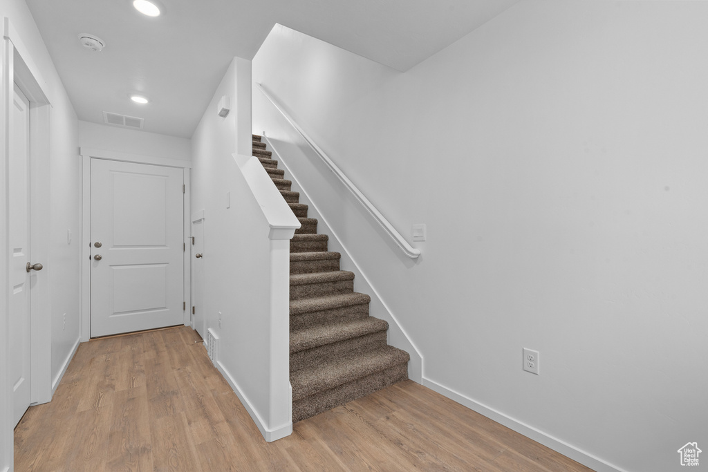 Stairway with wood finished floors, baseboards, and recessed lighting