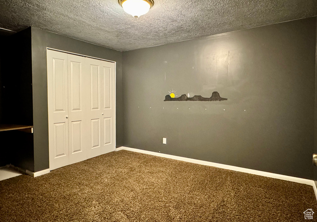 Unfurnished bedroom featuring carpet, a closet, a textured ceiling, and baseboards