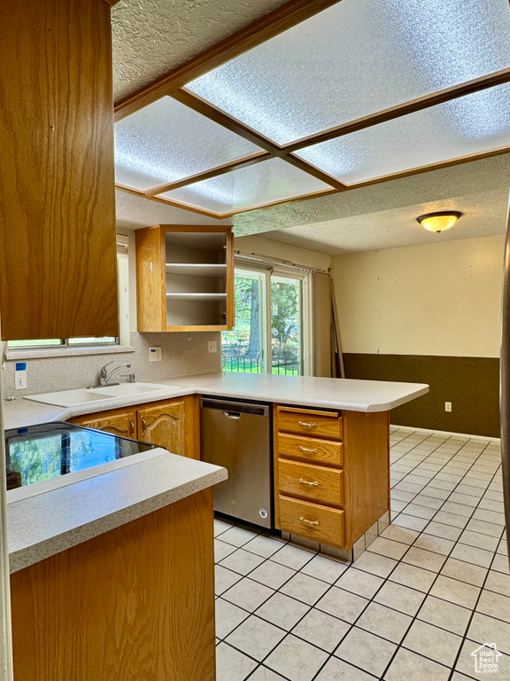 Kitchen featuring dishwasher, a sink, a peninsula, a textured ceiling, and light countertops