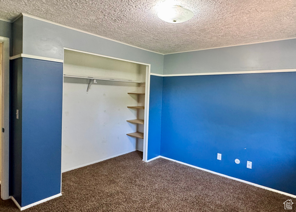 Unfurnished bedroom featuring a textured ceiling, carpet flooring, a closet, and baseboards