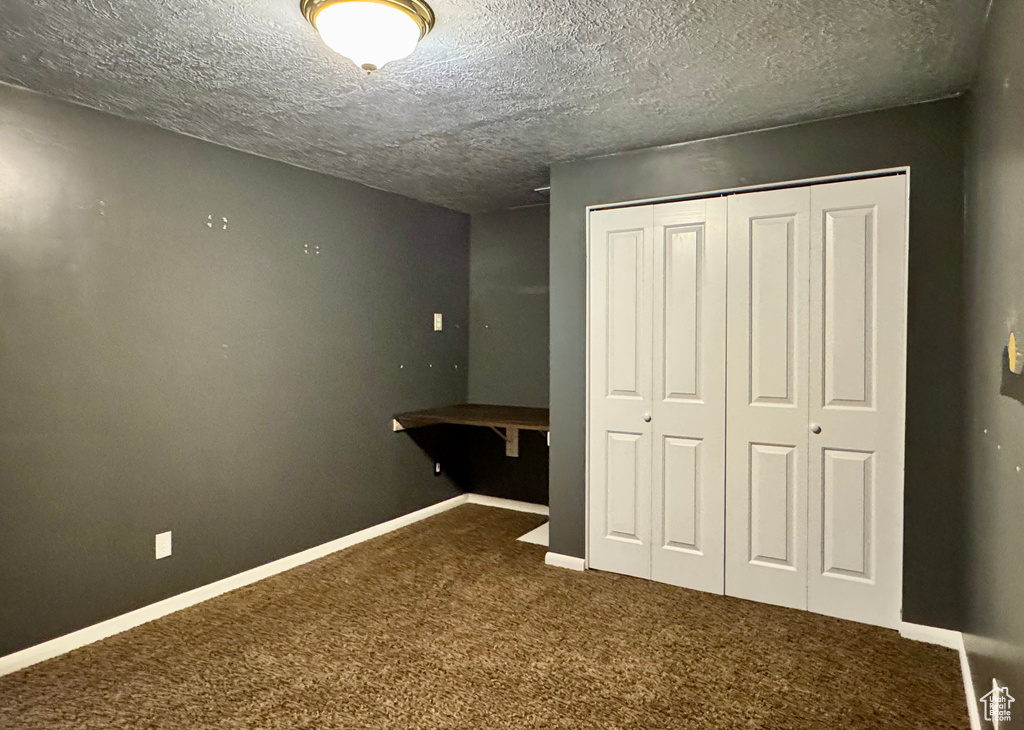 Unfurnished bedroom with carpet floors, a closet, a textured ceiling, and baseboards