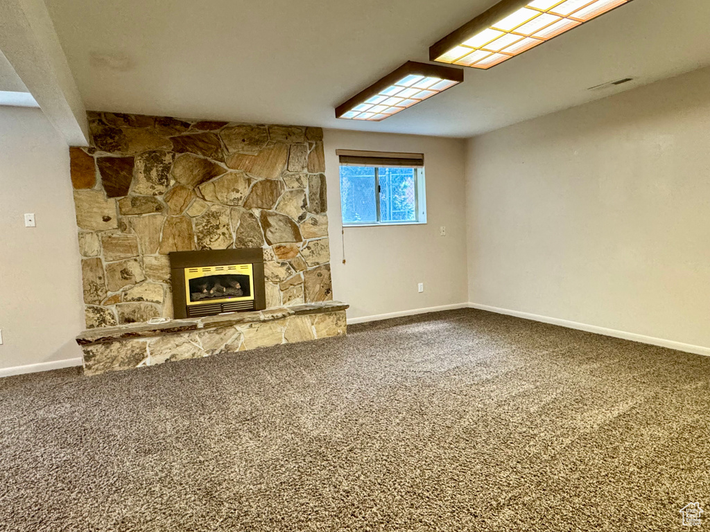 Unfurnished living room featuring carpet floors, baseboards, and a fireplace
