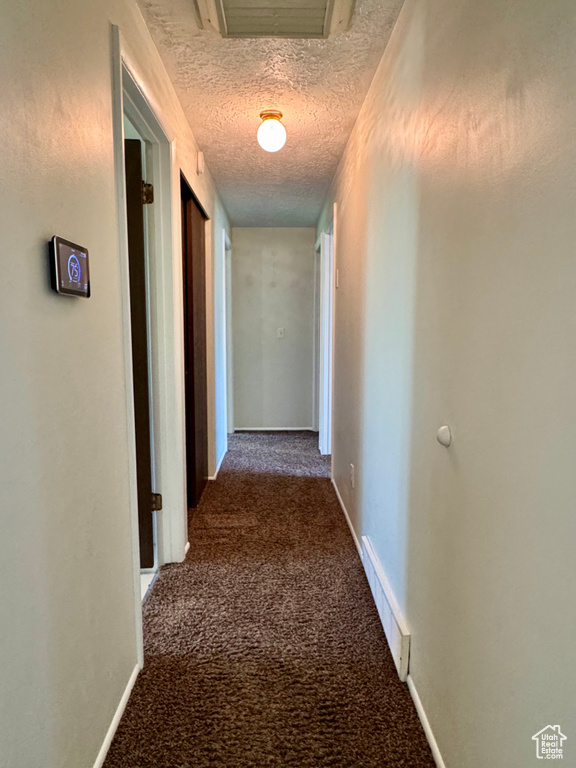 Hall with carpet floors, a textured ceiling, and baseboards