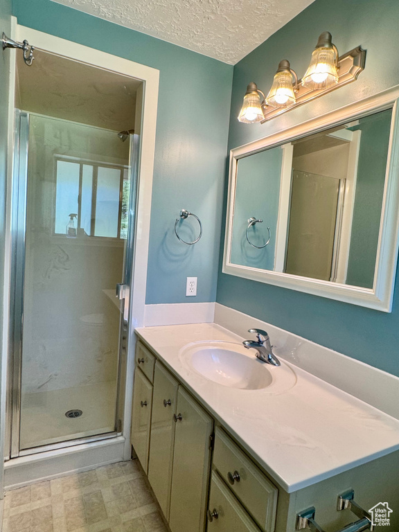 Bathroom featuring vanity, a stall shower, and a textured ceiling
